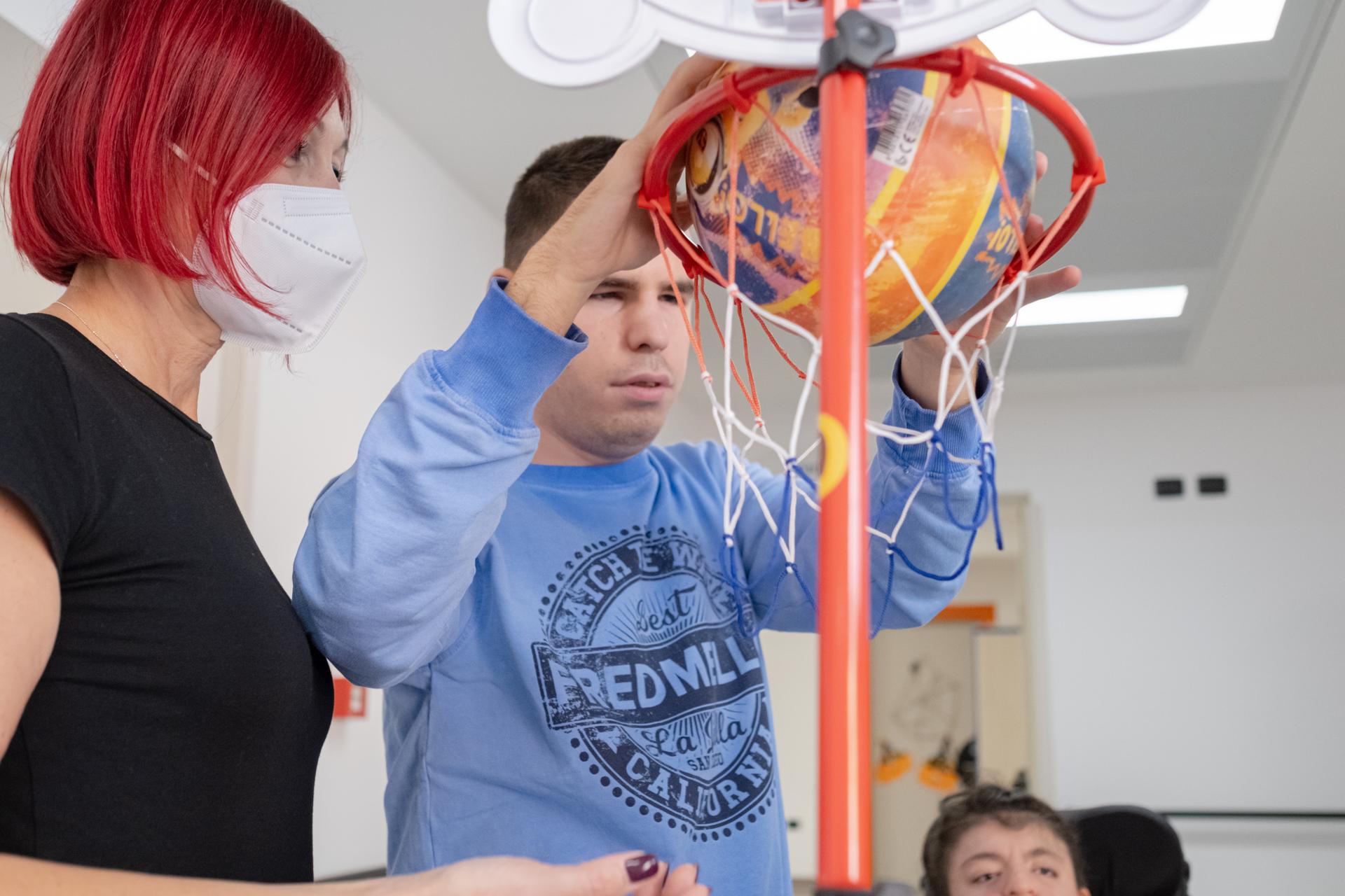 Benedetto gioca a basket presso il Centro diurno della Lega del Filo d'Oro. Nella foto è insieme alla sua educatrice Maria Grazia.