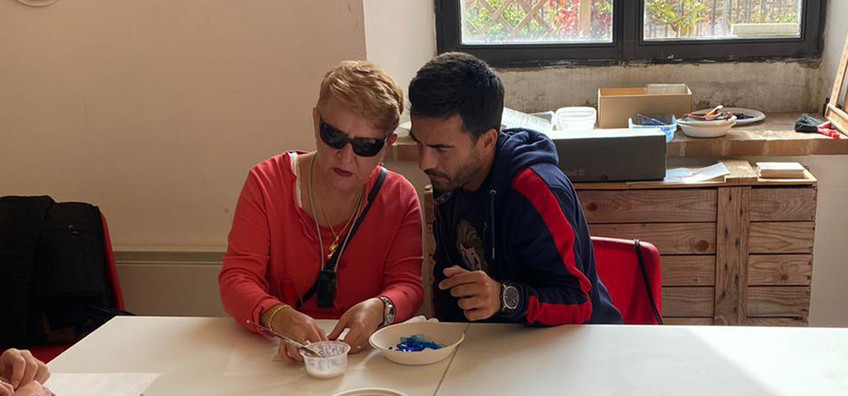 Alessandro, volontario alla Sede della Lega del Filo d'Oro di Pisa, insieme a Cristina, persona sordocieca, mentre fanno laboratorio di pittura