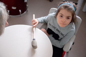 Letizia è seduta e suona il tamburo mentre guarda la telecamera