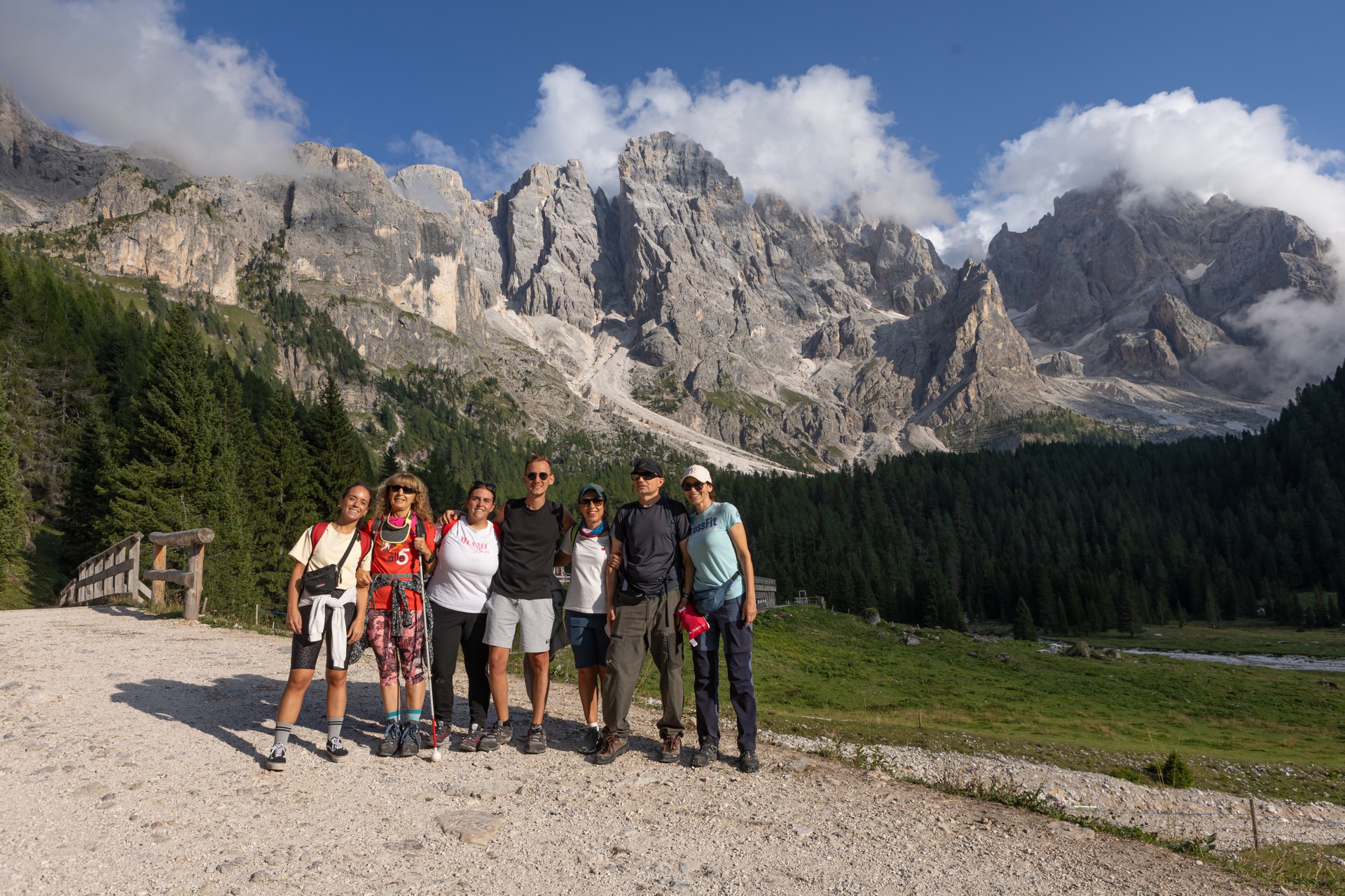 Foto di gruppo per volontari e persone sordocieche durante il soggiorno estivo a Predazzo, in montagna, che si vede nello sfondo della foto.