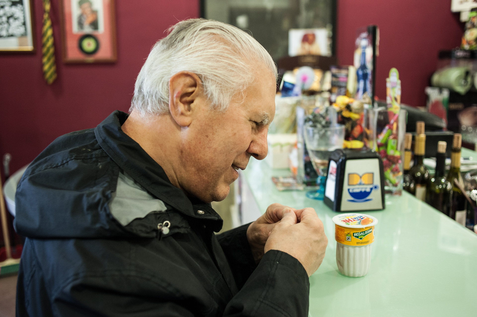 Angelo, utente anziano del Centro di Osimo, in piedi al bancone di un bar con davanti una bevanda