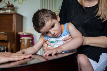 Musicoterapia alla Lega del Filo d'Oro: il piccolo Nicolò tiene le mani sulla chitarra per sentire le vibrazioni del suono