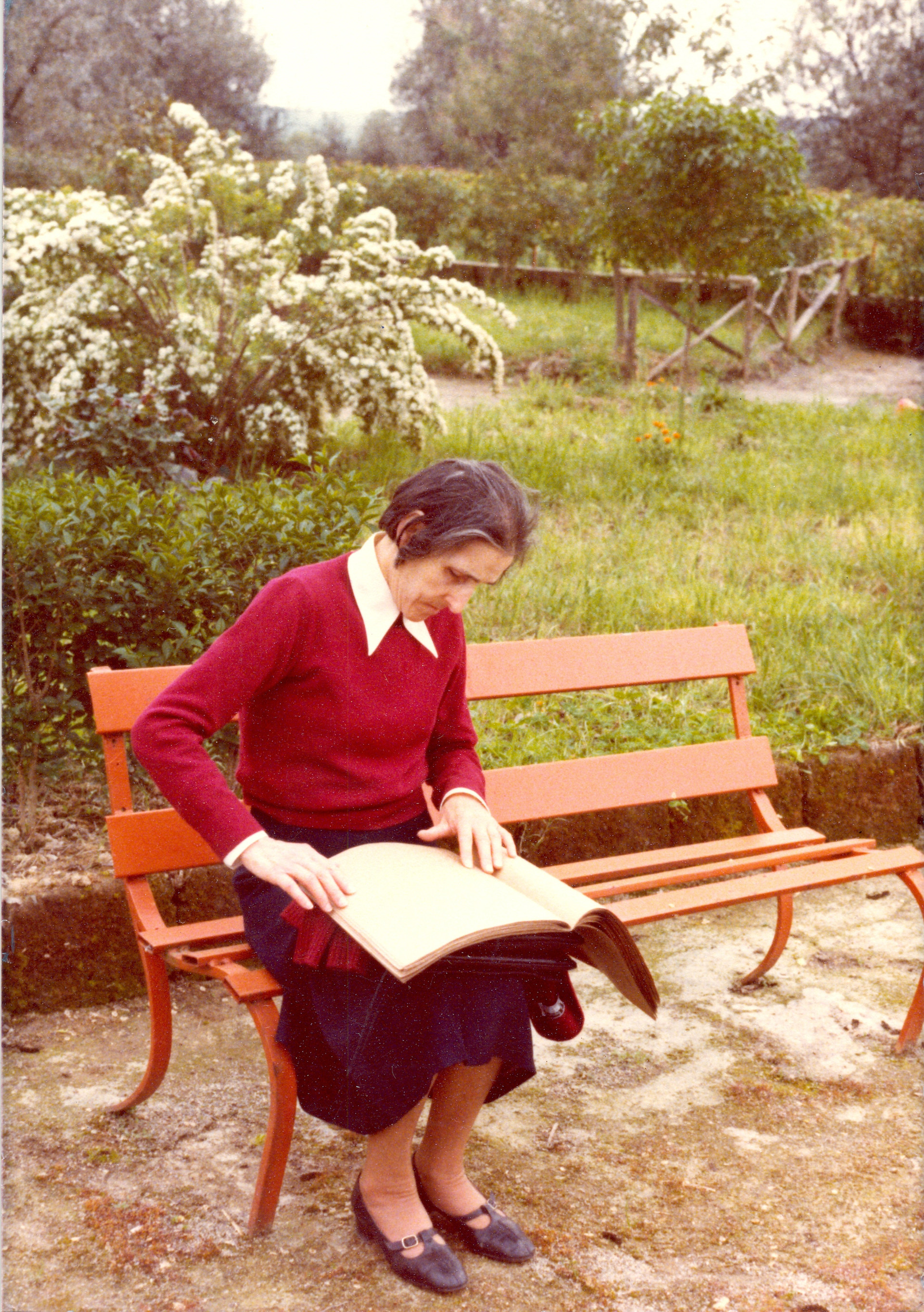 Sabina Santilli è seduta su una panchina e legge un libro in braille