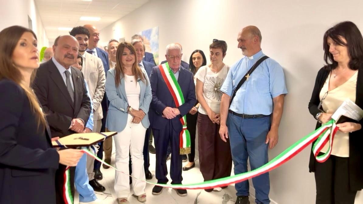 Nello scatto un momento simbolico del taglio del nastro avvenuto per la presentazione della Sede Territoriale di Rende. Un gruppo di rappresentati della Lega del Filo d'Oro e delle istituzioni locali sono riunite in un corridoio luminoso durante il taglio del nastro tricolore. 