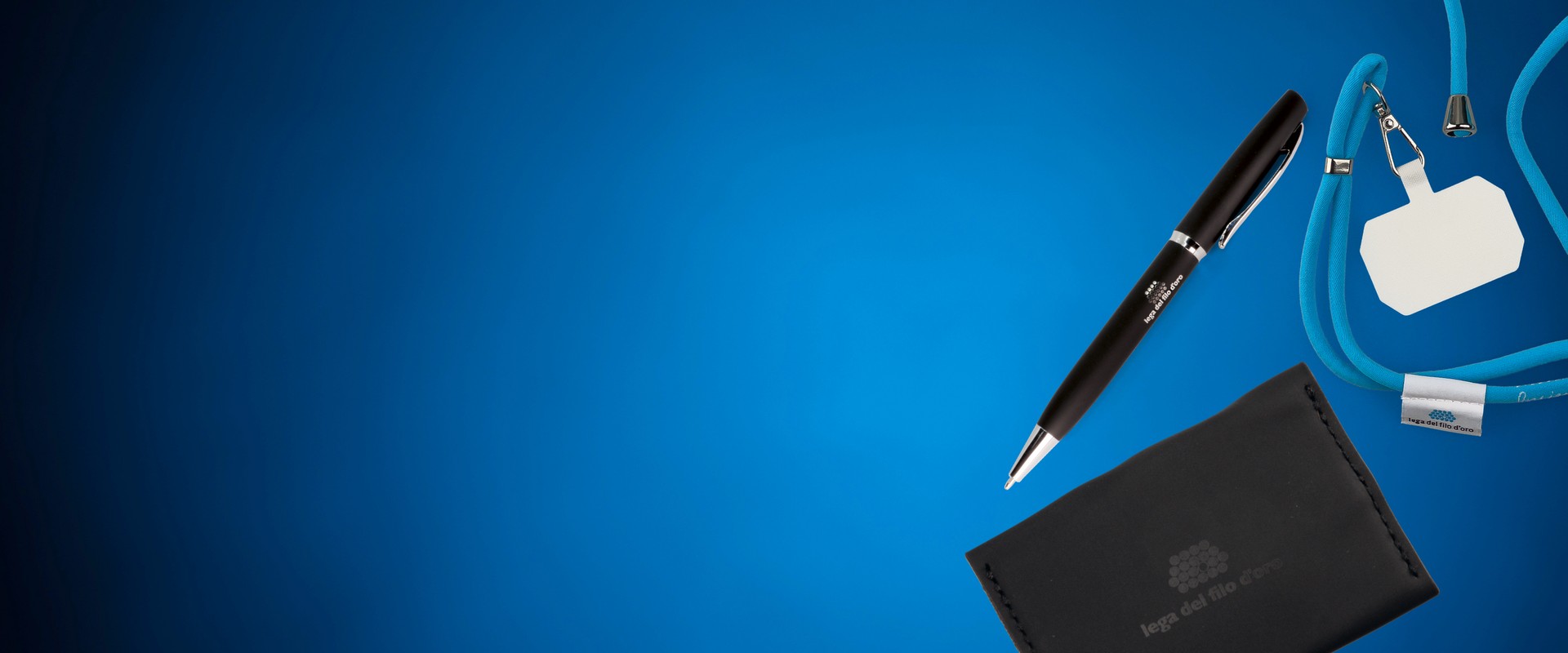 Foto su sfondo azzurro di un laccetto per smartphone, una penna e un portatessere: alcuni dei prodotti solidali ordinabili sul sito della Lega del Filo d'Oro