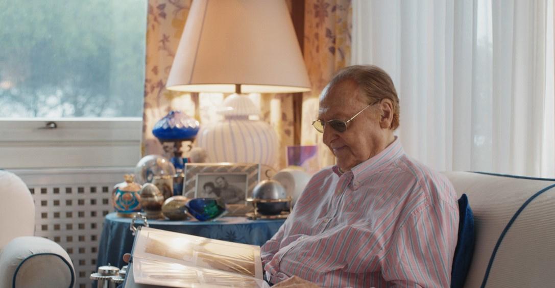 Una foto di Renzo Arbore durante il set di campagna del 60°, seduto nella sua casa a Roma mentre sfoglia un album di foto ricordando i 60 anni della Lega del Filo d'Oro.