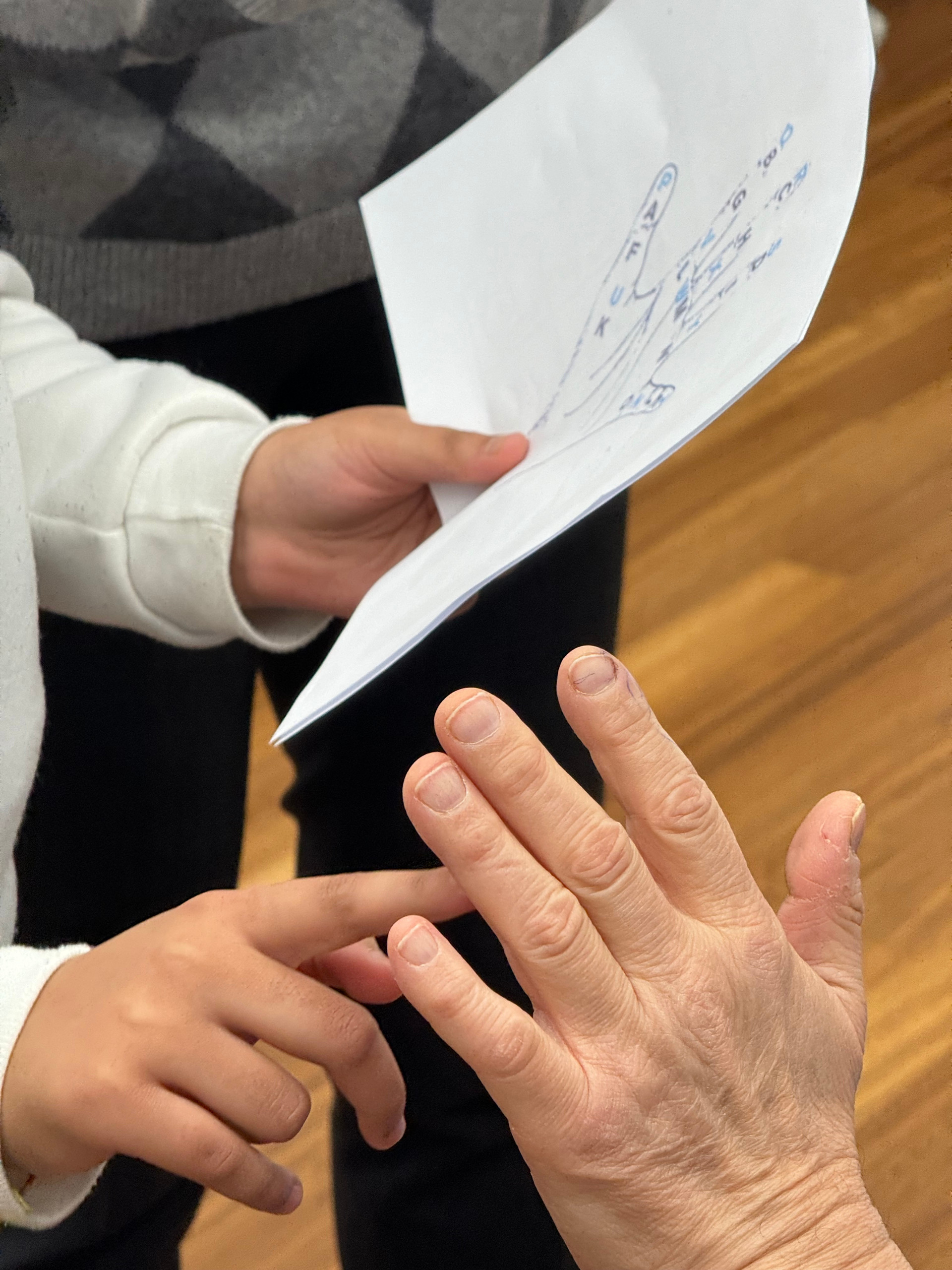 Gruppi e scuole in visita alla Lega del Filo d’Oro: primo piano di due mani che cercano di imparare il Malossi