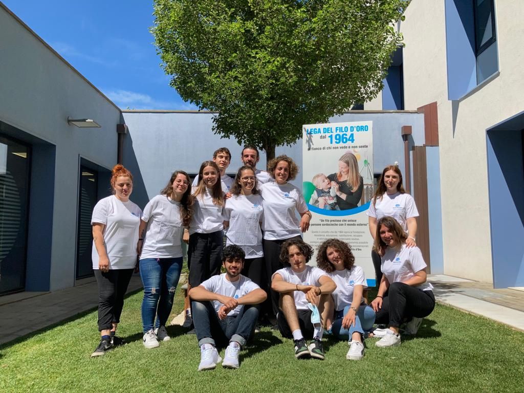Un gruppo di ragazzi posa sorridente in una delle aree verdi della Lega del Filo d’Oro.