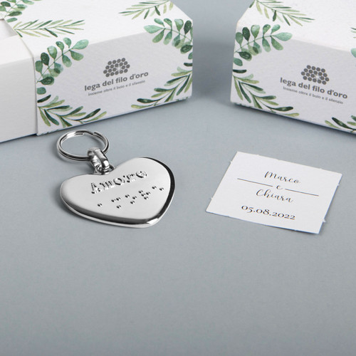 Still life su sfondo grigio del portachiavi cuore , con la sua bomboniera green e il biglietto di accompagnamento 51