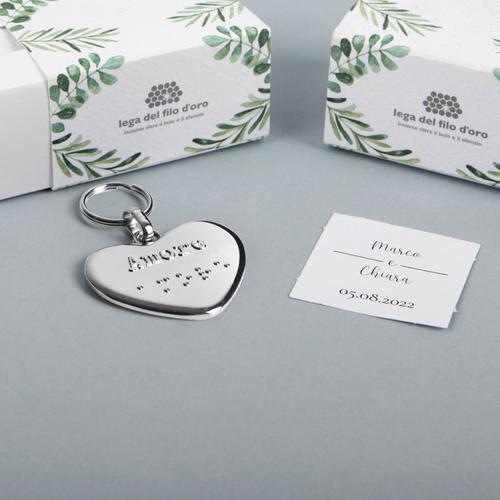 Still life su sfondo grigio del portachiavi cuore , con la sua bomboniera green e il biglietto di accompagnamento 55