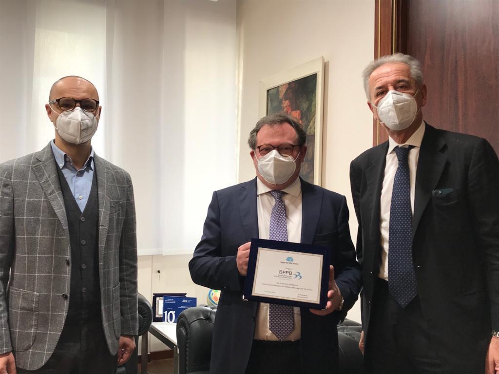 Tre uomini in abbigliamento formale mostrano la targa appena consegnata loro dalla Lega Del Filo d'Oro