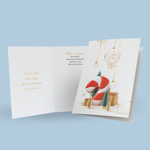 Il biglietto per augurare buone feste con raffigurati un bastoncino candito a strisce rosse e bianche circondato da pacchetti regalo dorati, abeti e tante palline di natale luccicanti. A fianco è visibile il biglietto aperto con il suo messaggio di auguri.