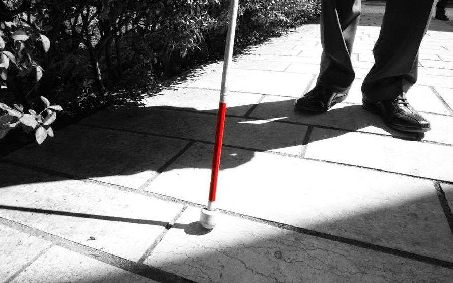 Immagine in bianco e nero di un bastone bianco e rosso per sordociechi. L'unica parte colorata è il rosso, mettendo in evidenza l'oggetto.