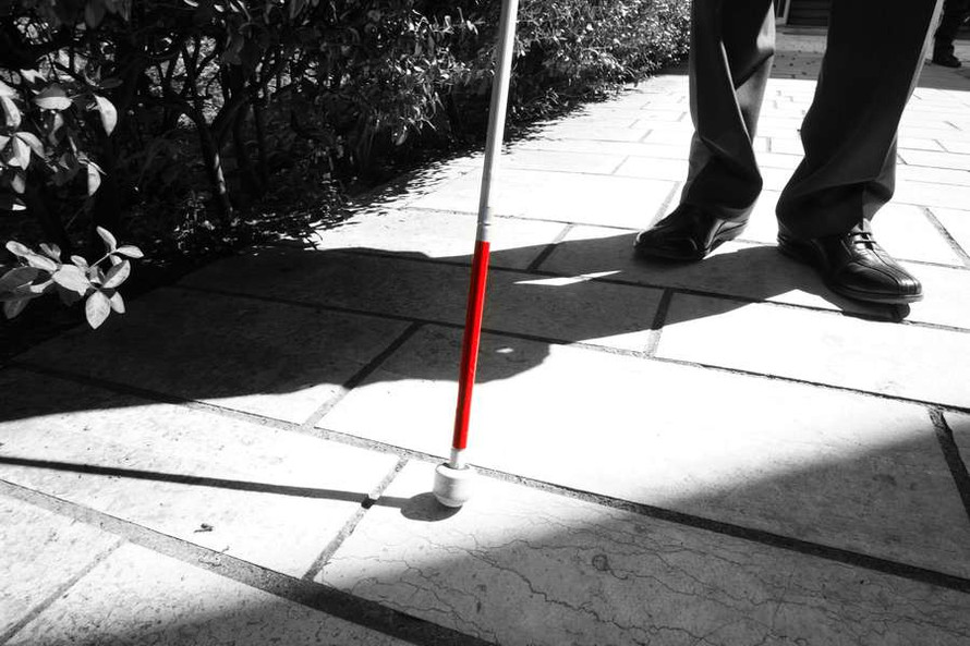 Immagine in bianco e nero di un bastone bianco e rosso per sordociechi. L'unica parte colorata è il rosso, mettendo in evidenza l'oggetto.