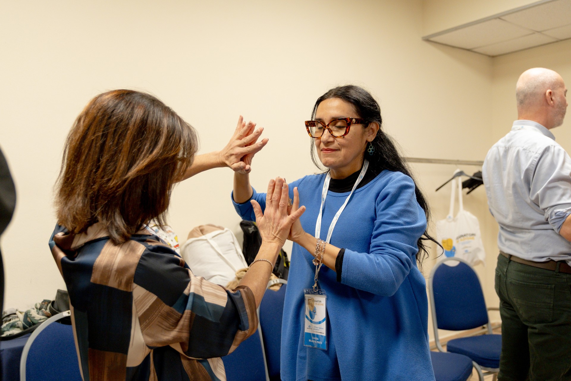 Due partecipanti al Forum dei Volontari si toccano le mani durante un’attività di gruppo. Un gesto di connessione, comunicazione e condivisione che esprime inclusione, relazione e partecipazione attiva.