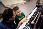 Leonardo bambino utente nel Centro Nazionale di Osimo con Fiammetta, musicoterapista, suona i tasti di un pianoforte