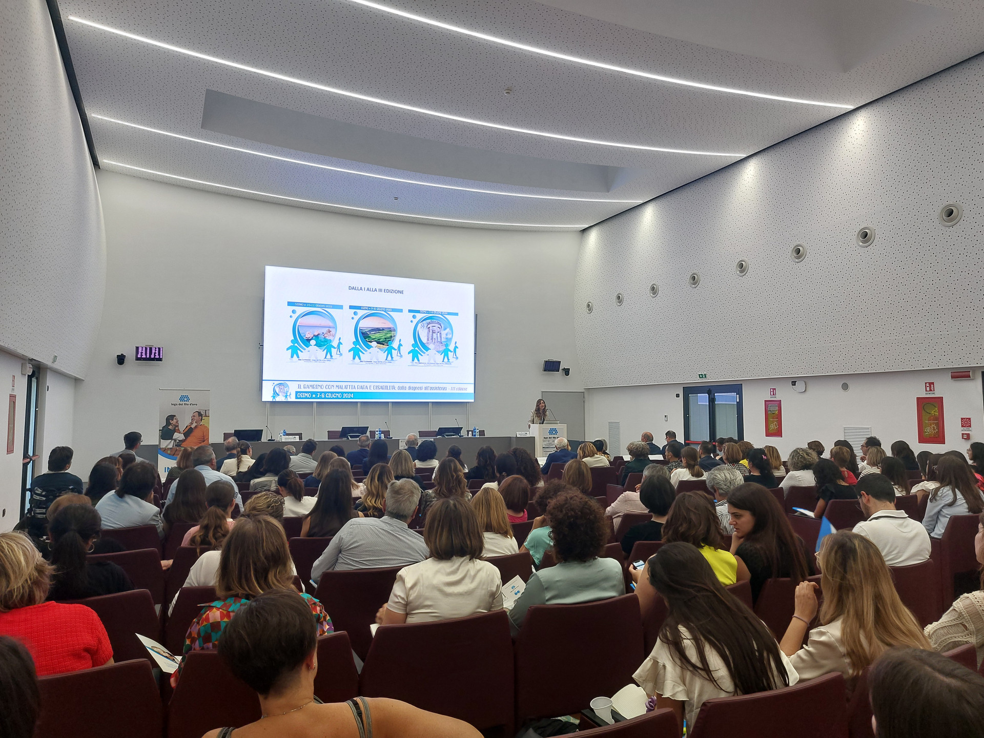 La platea assiste a un convegno all’interno della Sala Conferenze del Centro Nazionale della Fondazione Lega del Filo d’Oro. 