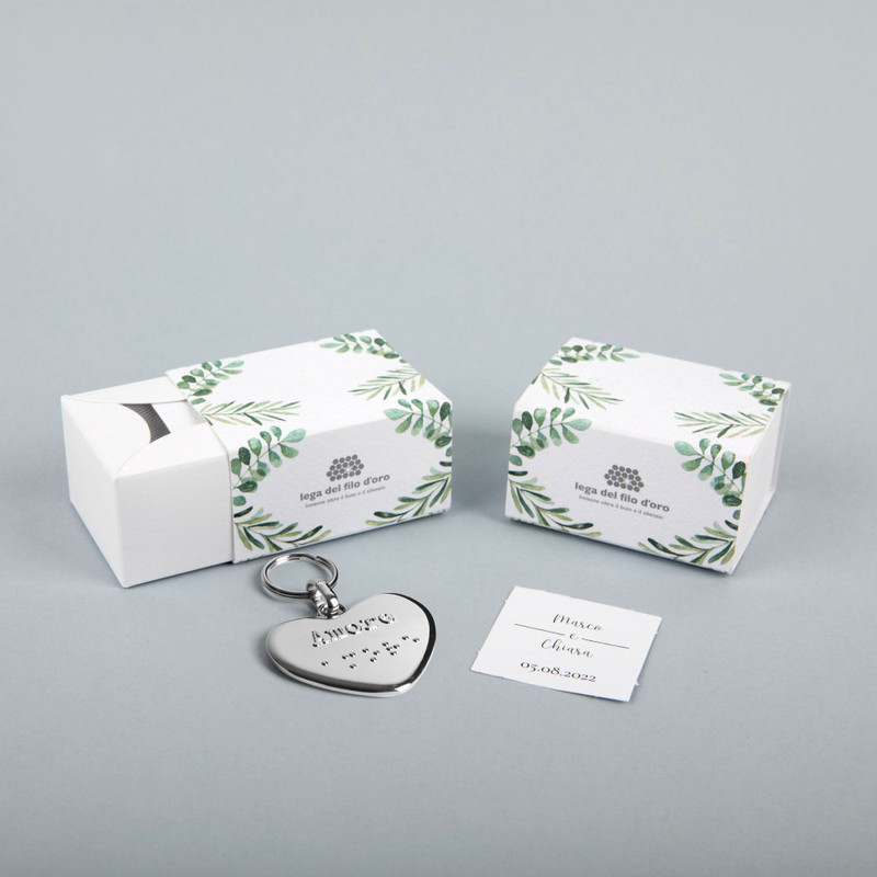 Still life su sfondo grigio della bomboniera green accompagnata dal suo portachiavi cuore e bigliettino personalizzato