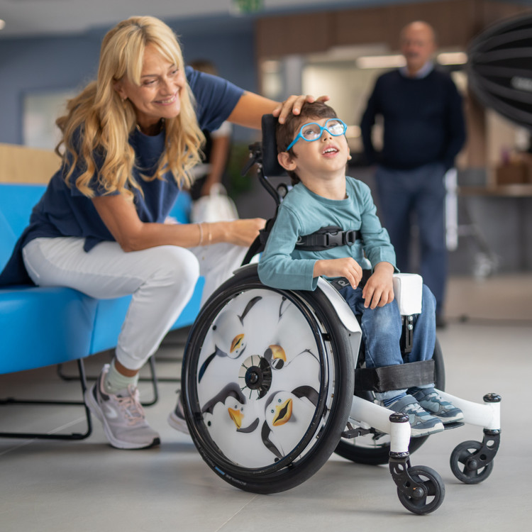 Nicola, bambino seguito dalla Lega dle Filo d'Oro, insieme alla fisioterapista, Francesca. Sono all'ingresso del Centro Nazionale di Osimo e ridono