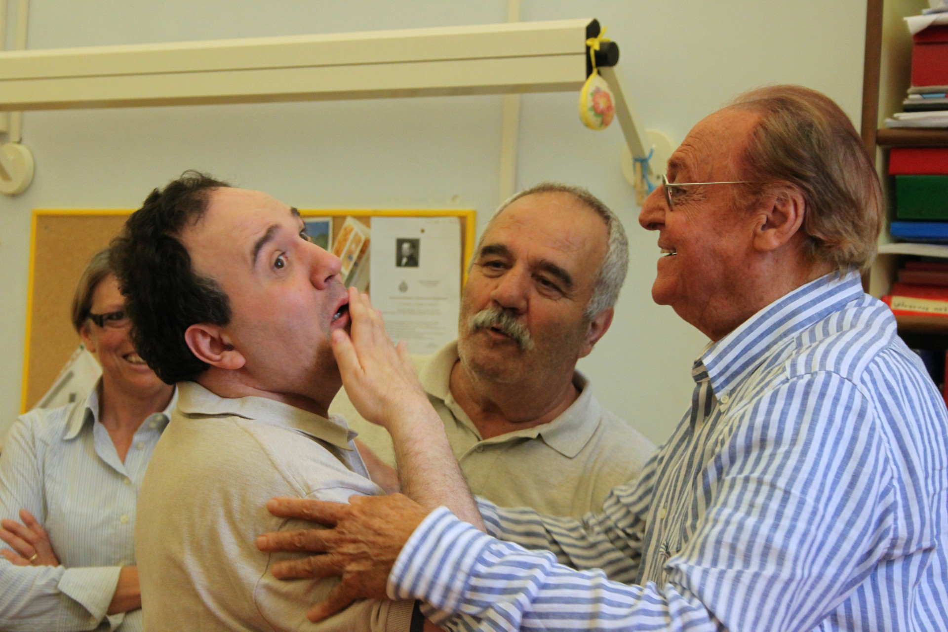 Renzo Arbore incontra Alberto, utente adulto del Centro di Osimo, e lo saluta mettendogli le mani sulle spalle, Alberto risponde con il linguaggio gestuale mentre il papà Gianfranco assiste alla scena.