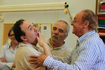 Renzo Arbore incontra Alberto, utente adulto del Centro di Osimo, e lo saluta mettendogli le mani sulle spalle, Alberto risponde con il linguaggio gestuale mentre il papà Gianfranco assiste alla scena.