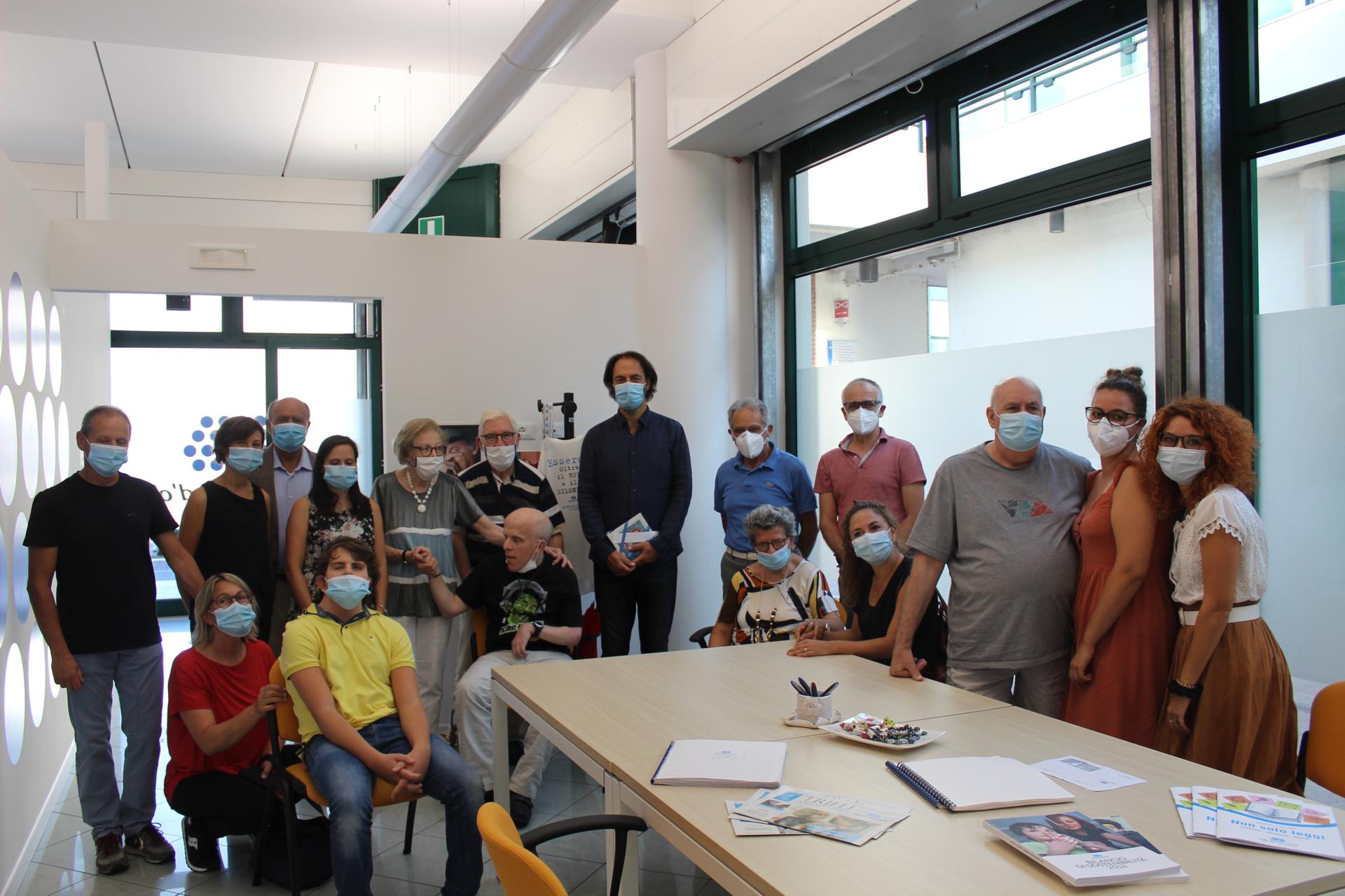 Neri Marcorè, testimonial della Lega del Filo d'Oro, circondato di utenti, famigliari e personale della Sede di Padova durante una visita. Tutti i presenti indossano mascherine chirurgiche