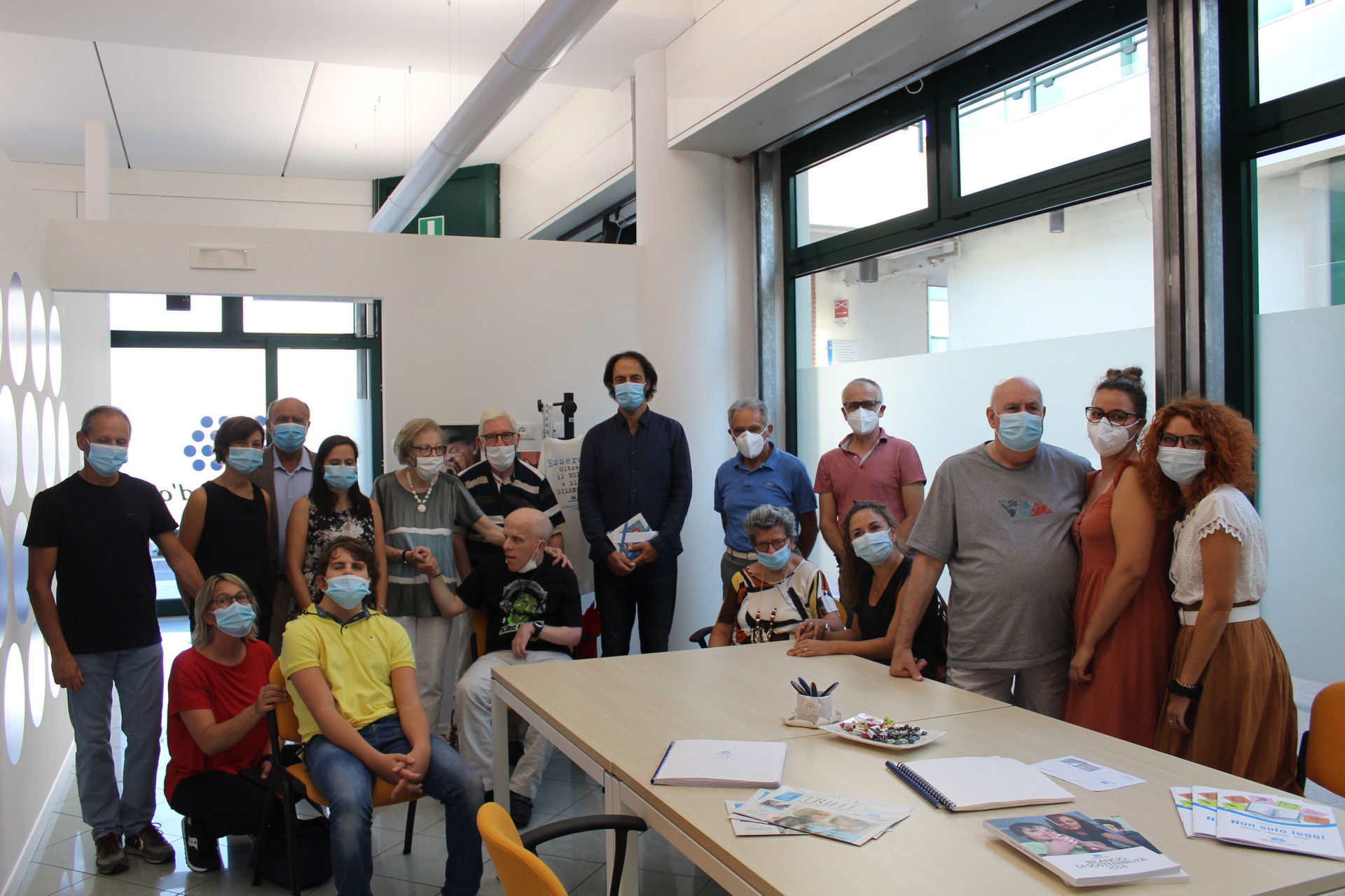 Neri Marcorè, testimonial della Lega del Filo d'Oro, circondato di utenti, famigliari e personale della Sede di Padova durante una visita. Tutti i presenti indossano mascherine chirurgiche