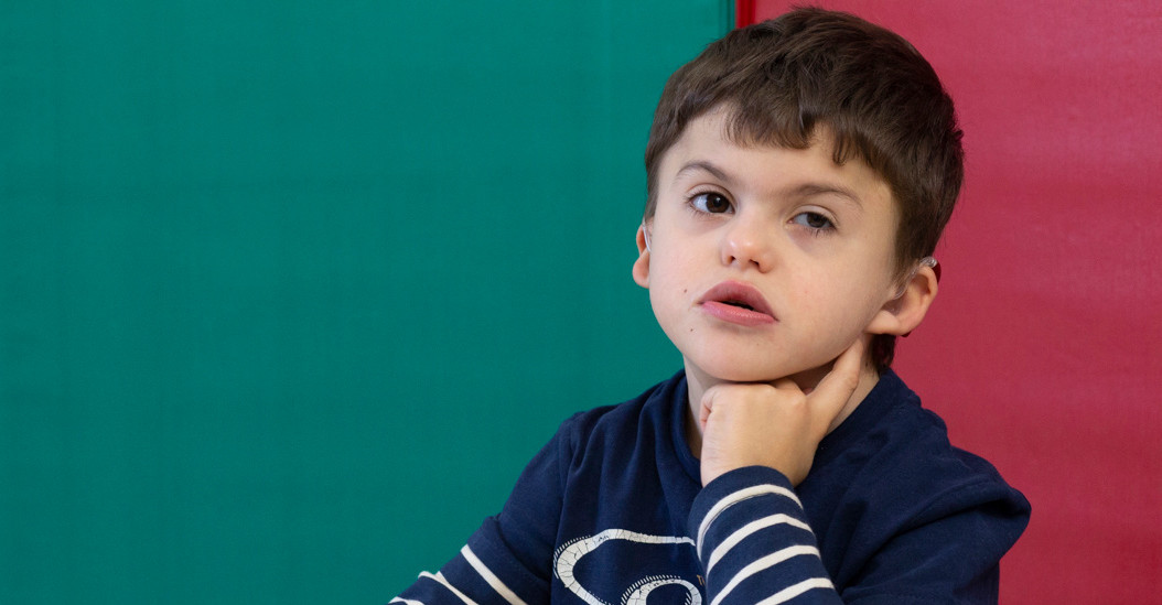 Agostino, bambino di 8 anni con sindrome di Charge, è seduto tranquillo a un banco in attesa di svolgere una attività educativa 