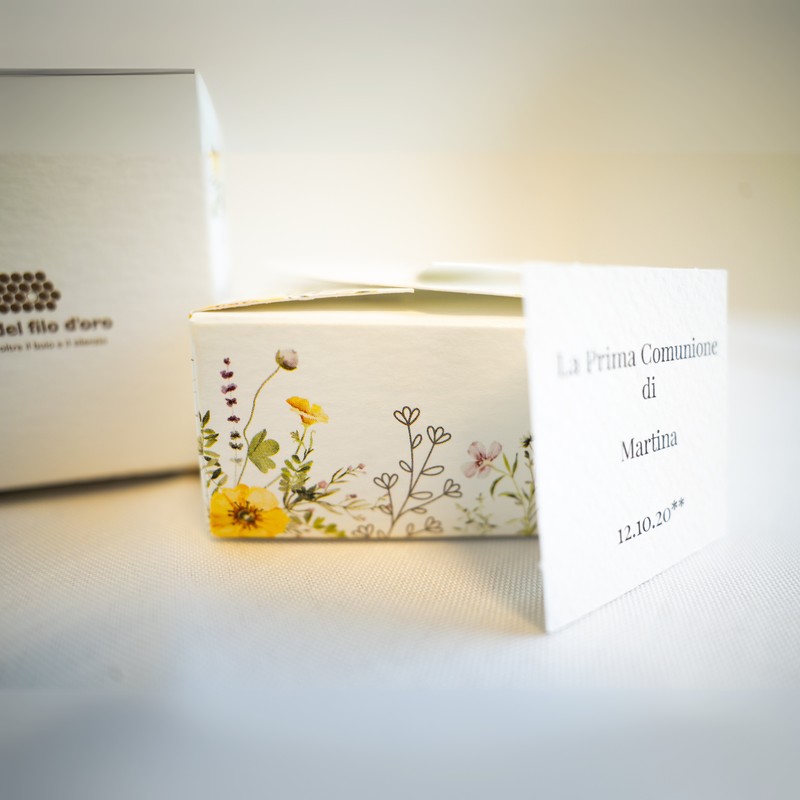 Bomboniera Floreale Lega del Filo d'Oro, in cartoncino bianco con una fantasia a fiori di campo e una romantica chiusura a cuore. Accompagnata da bigliettino personalizzabile