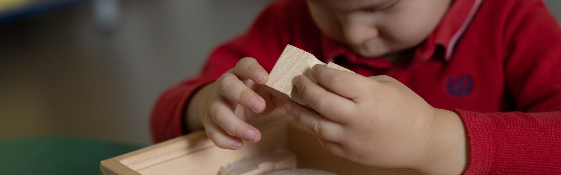 Piccolo utente al Centro Diagnostico di Osimo esplora con le manine diversi oggetti in legno ricoperti di diversi materiali per la stimolazione tattile