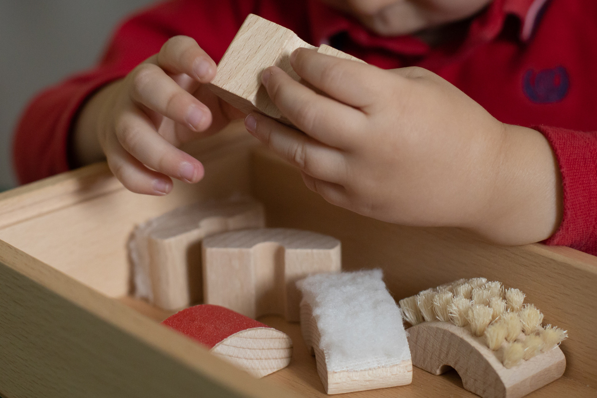 Piccolo utente al Centro Diagnostico di Osimo esplora con le manine diversi oggetti in legno ricoperti di diversi materiali per la stimolazione tattile