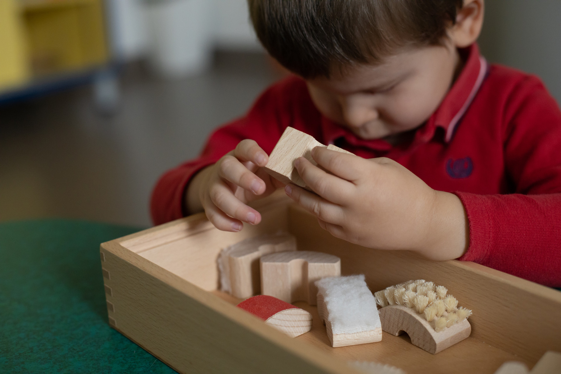 Piccolo utente al Centro Diagnostico di Osimo esplora con le manine diversi oggetti in legno ricoperti di diversi materiali per la stimolazione tattile