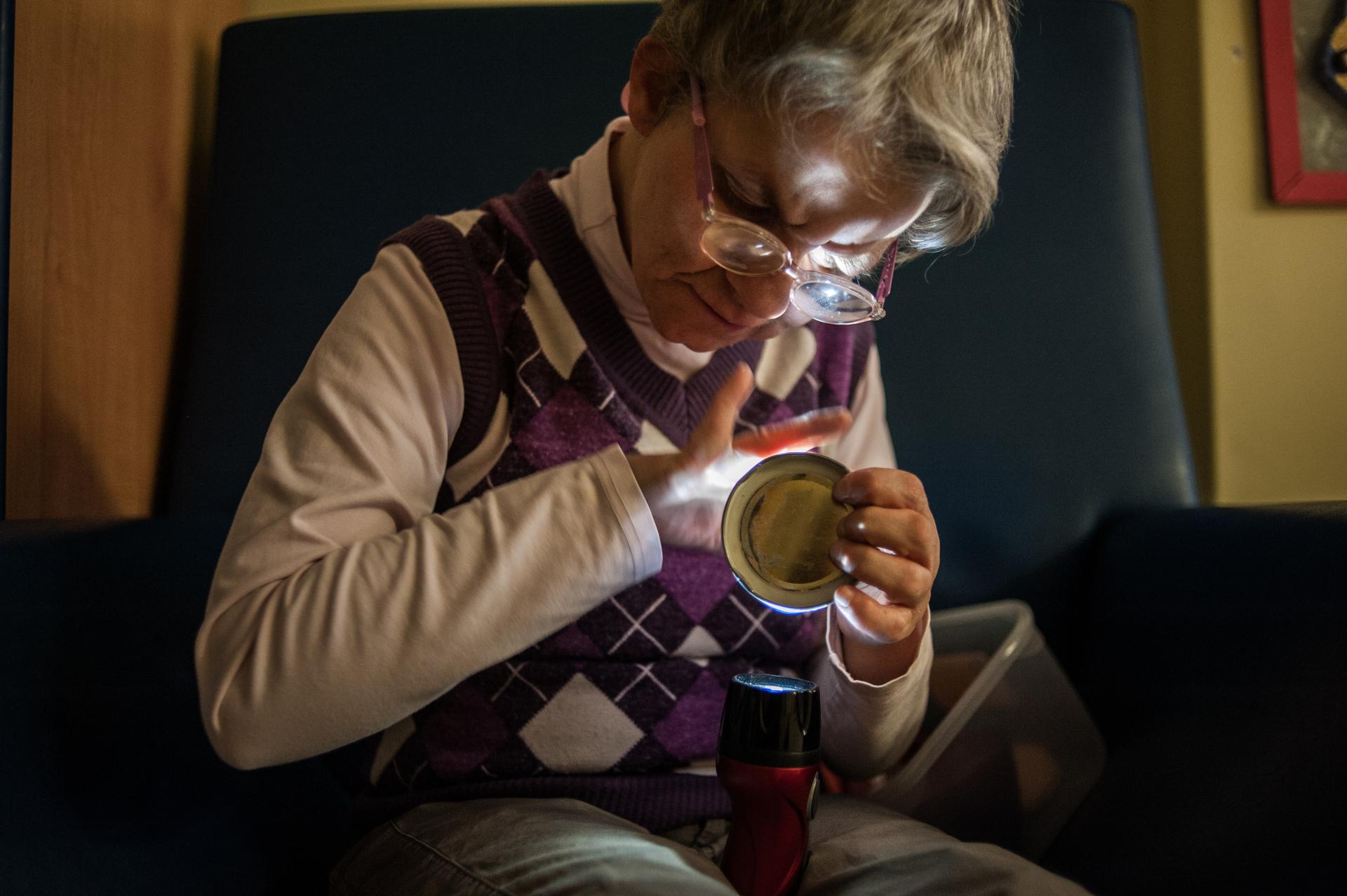 Laura, utente adulta del Centro di Lesmo, è seduta in poltrona e si rilassa osservando i bagliori di una torcia che tiene in mano