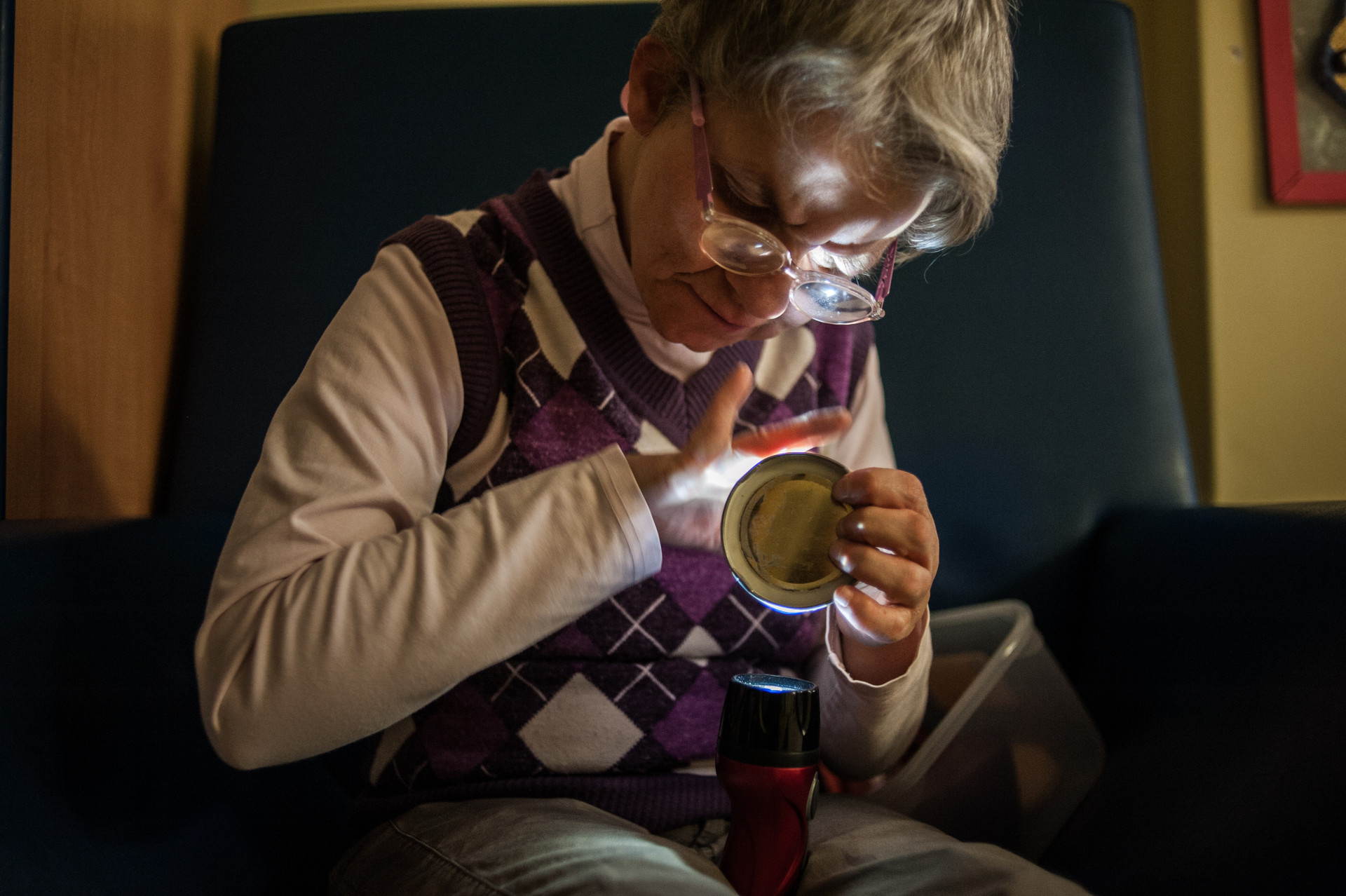 Laura, utente adulta del Centro di Lesmo, è seduta in poltrona e si rilassa osservando i bagliori di una torcia che tiene in mano