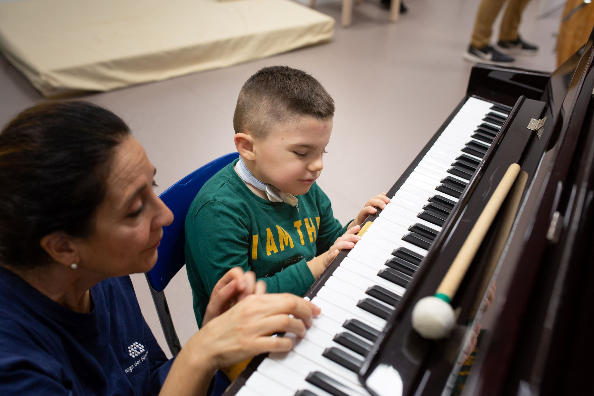 Leo, bambino seguito dalla Lega del Filo d'Oro, suona il pianoforte con Fiammetta durante l'attività di musicoterapia. Leo sorride.
