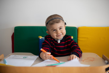 Berkay, bambino con la sindrome di Charge, seguito dalla Lega del Filo d'Oro, si trova nell'aula del Centro Nazionale al Diagnostico, mentre colora e sorride