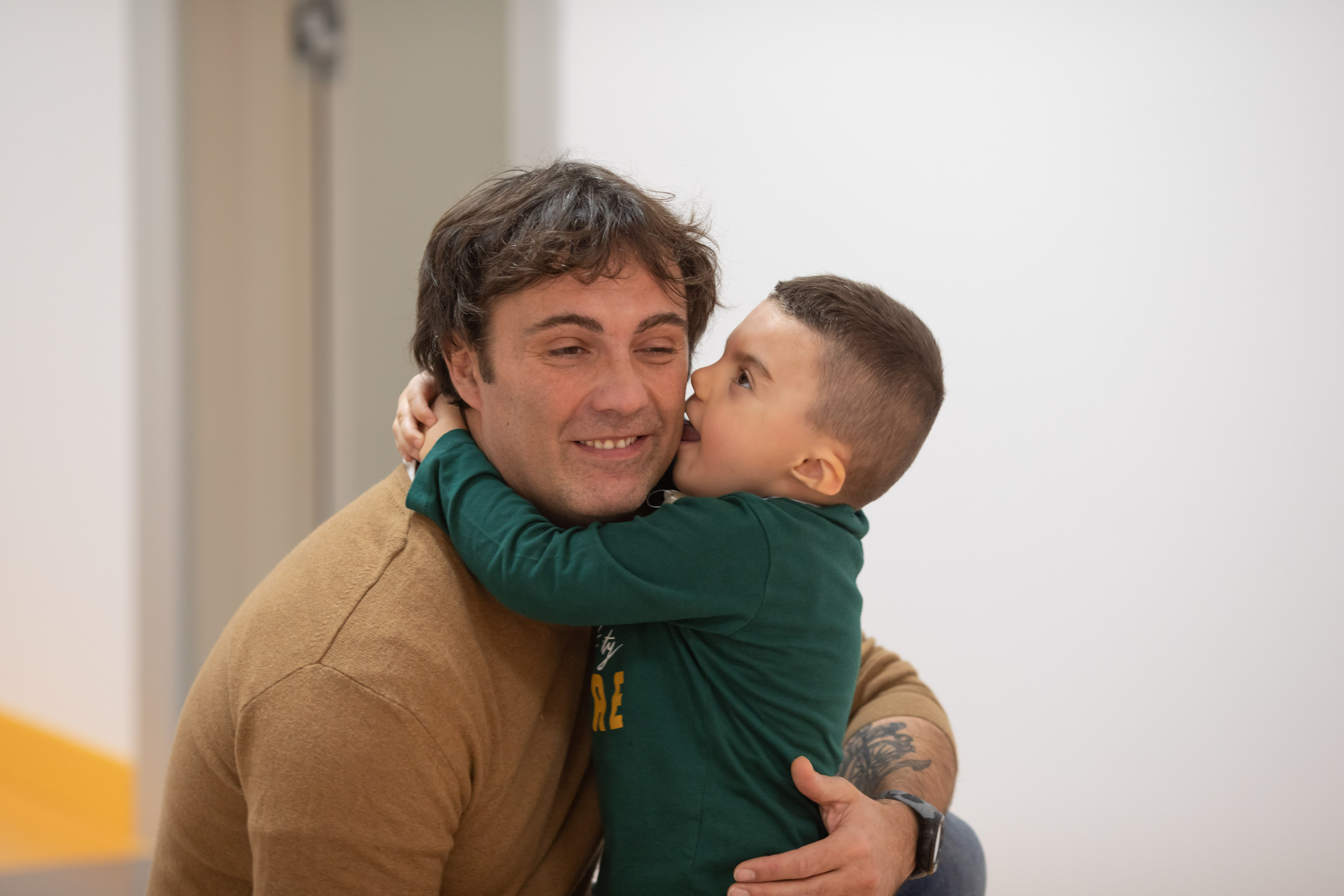 Leonardo, bambino con sindrome di Charge, dà un bacio al suo papà nei corridoi del Centro Nazionale