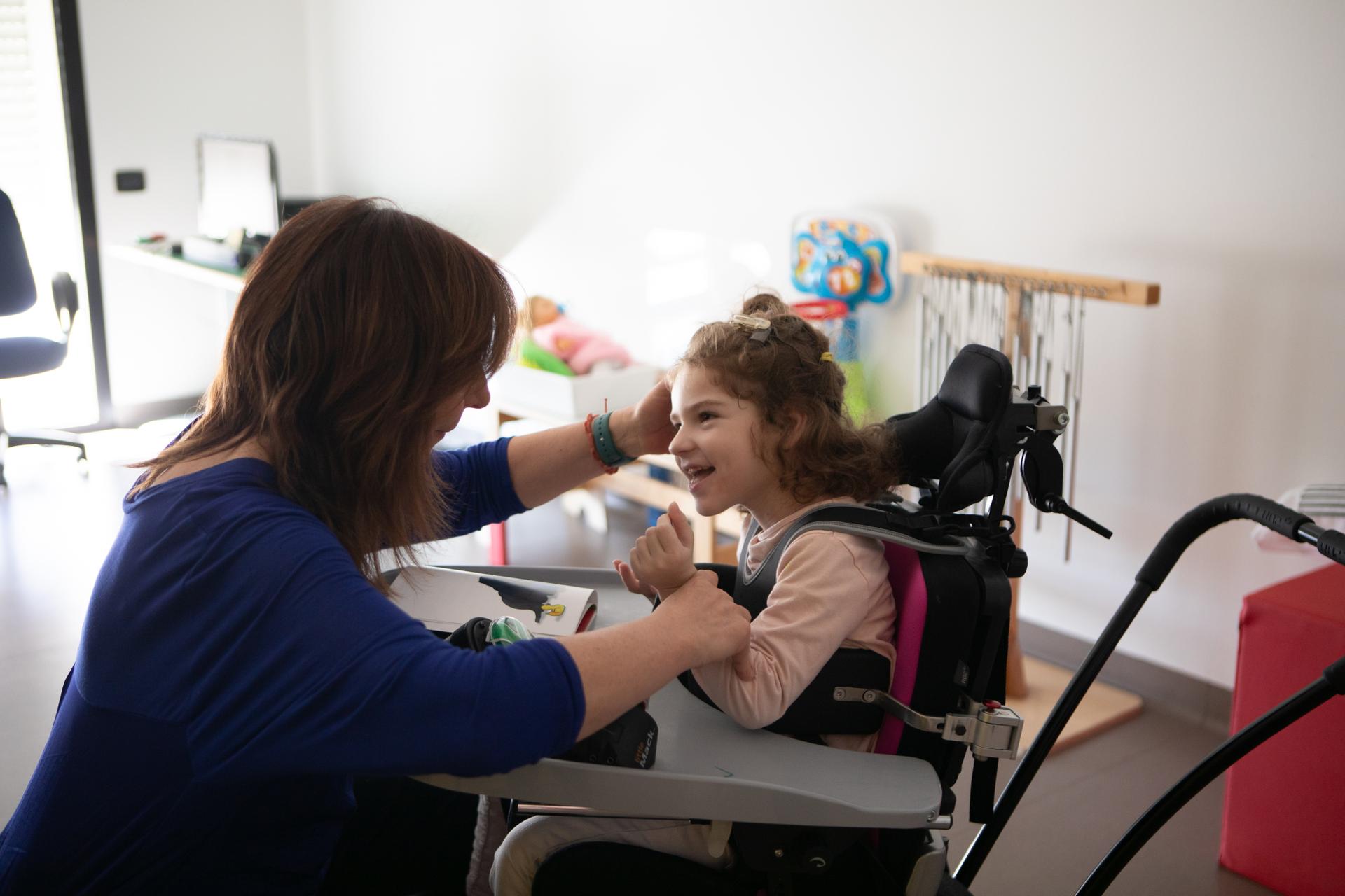 Melissa, bambina utente della Lega del Filo d’Oro, sorride felice mentre partecipa a un’attività con la sua educatrice.