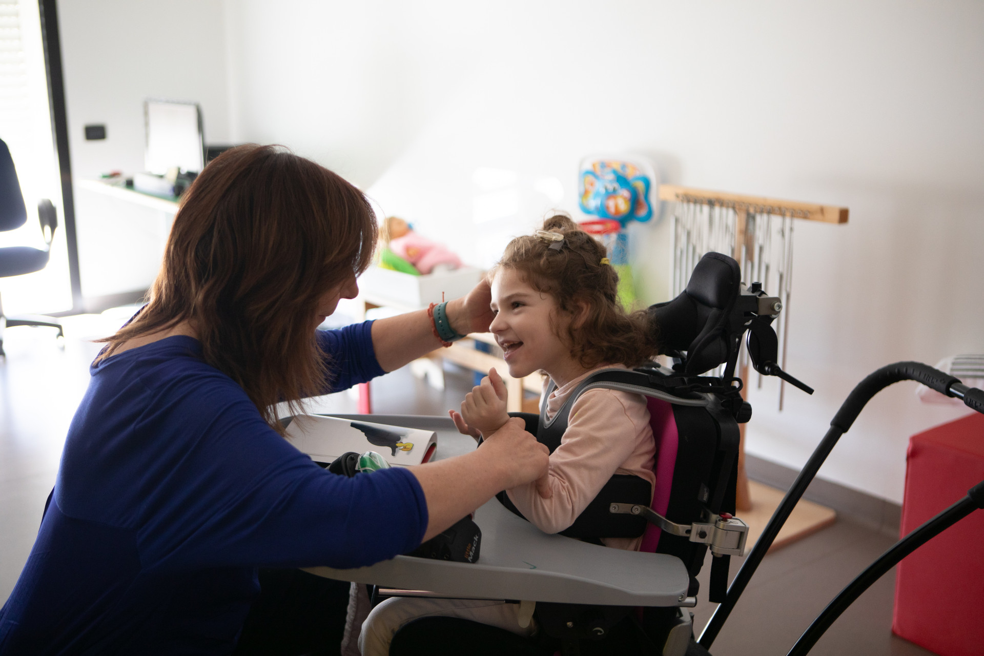Melissa, bambina utente della Lega del Filo d’Oro, sorride felice mentre partecipa a un’attività con la sua educatrice.