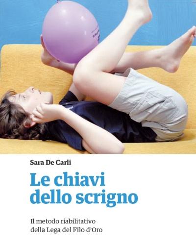 Copertina del libro "Le chiavi dello scrigno: il metodo riabilitativo della Lega del Filo d'Oro" a cura di Sara De Carli, con un bambino utente che gioca con un palloncino rosa.