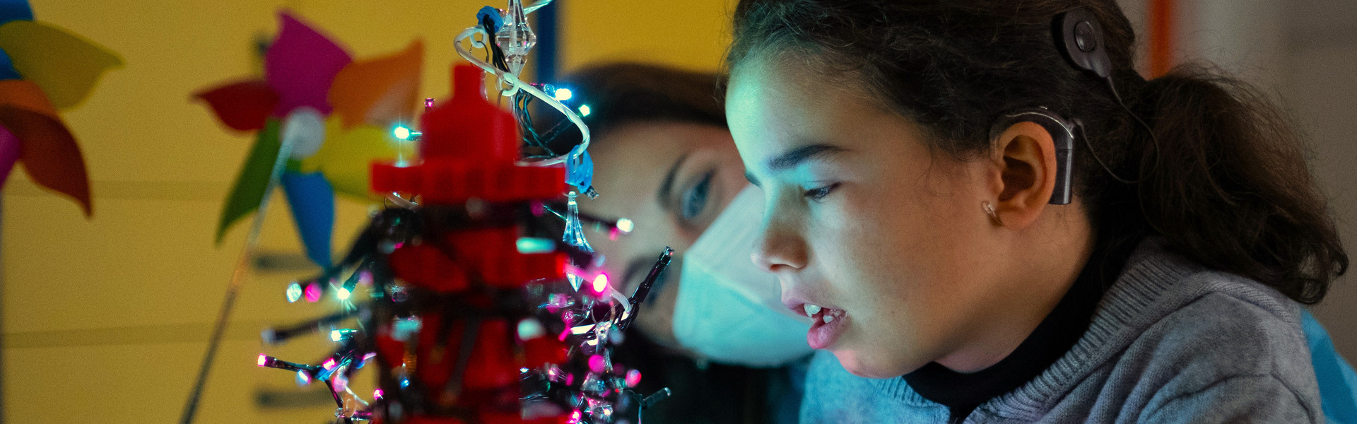 Giulia e Donatella insieme giocano nella stanza luminosa al Centro Nazionale di Osimo, con un piccolo albero di Natale tutto illuminato