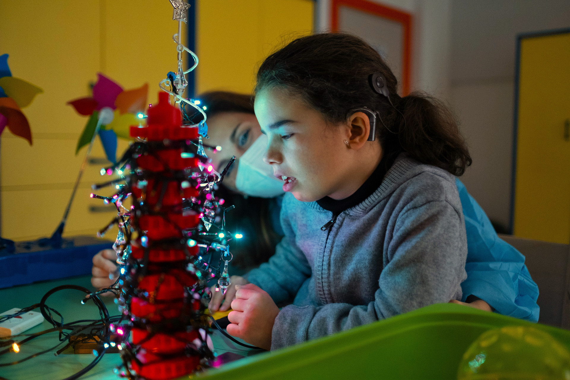 Giulia e Donatella insieme giocano nella stanza luminosa al Centro Nazionale di Osimo, con un piccolo albero di Natale tutto illuminato