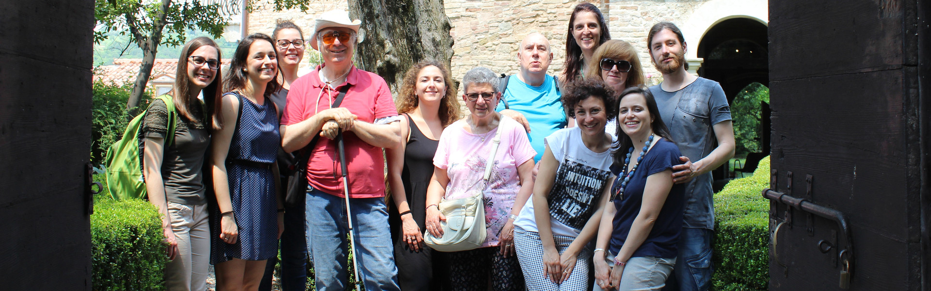 Foto di gruppo di utenti, volontari e parsonale della Sede di Padova in uscita. Alle loro spalle un palazzo antico