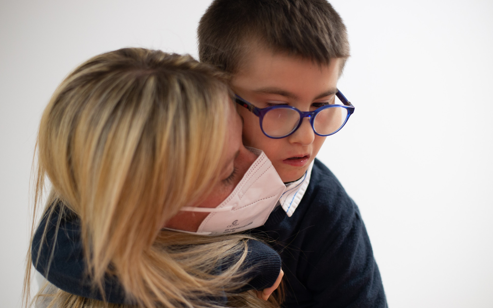 Biagio Luigi, bambino ospite del Centro di Osimo, è in braccio alla sua educatrice che indossa mascherina ffp2 e camice monouso anti covid