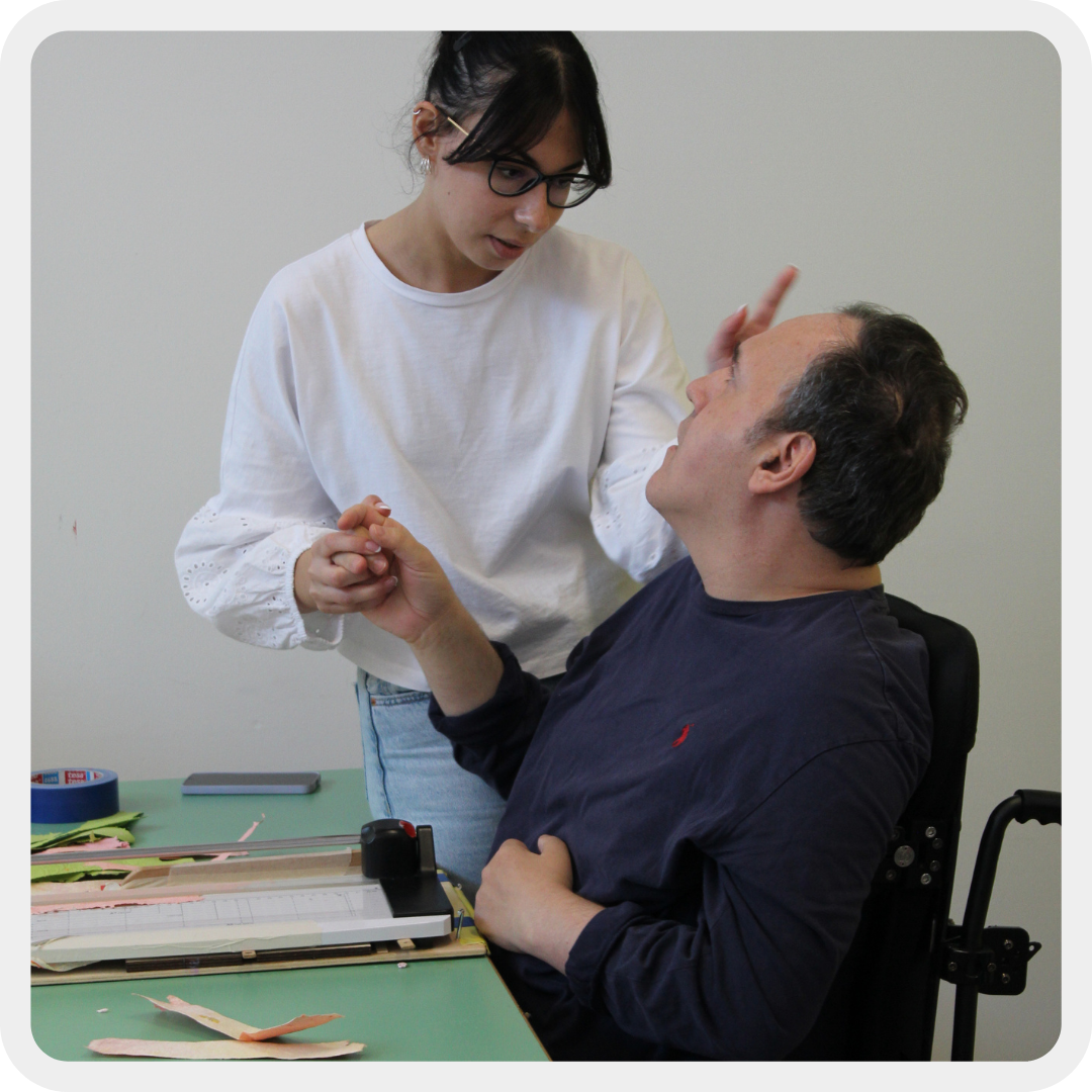 Alberto, adulto residenziale del Centro Nazionale di Osimo, mentre è in laboratorio a fare attività insieme alla sua educatrice e stanno parlando attraverso il linguaggio di comunicazione gestuale.