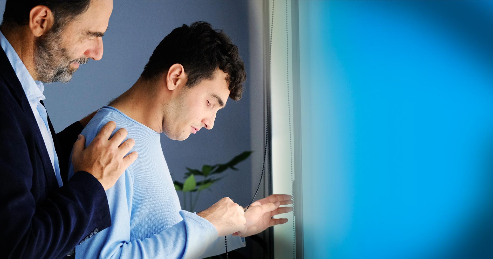 Foto di Neri Marcorè insieme a Francesco, ragazzo sordocieco. La foto è di profilo, Neri tiene le mani sulle spalle di Francesco. 