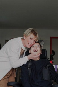 Bambino della Lega del Filo d'Oro sorridente abbracciato amorevolmente, mentre sorride.