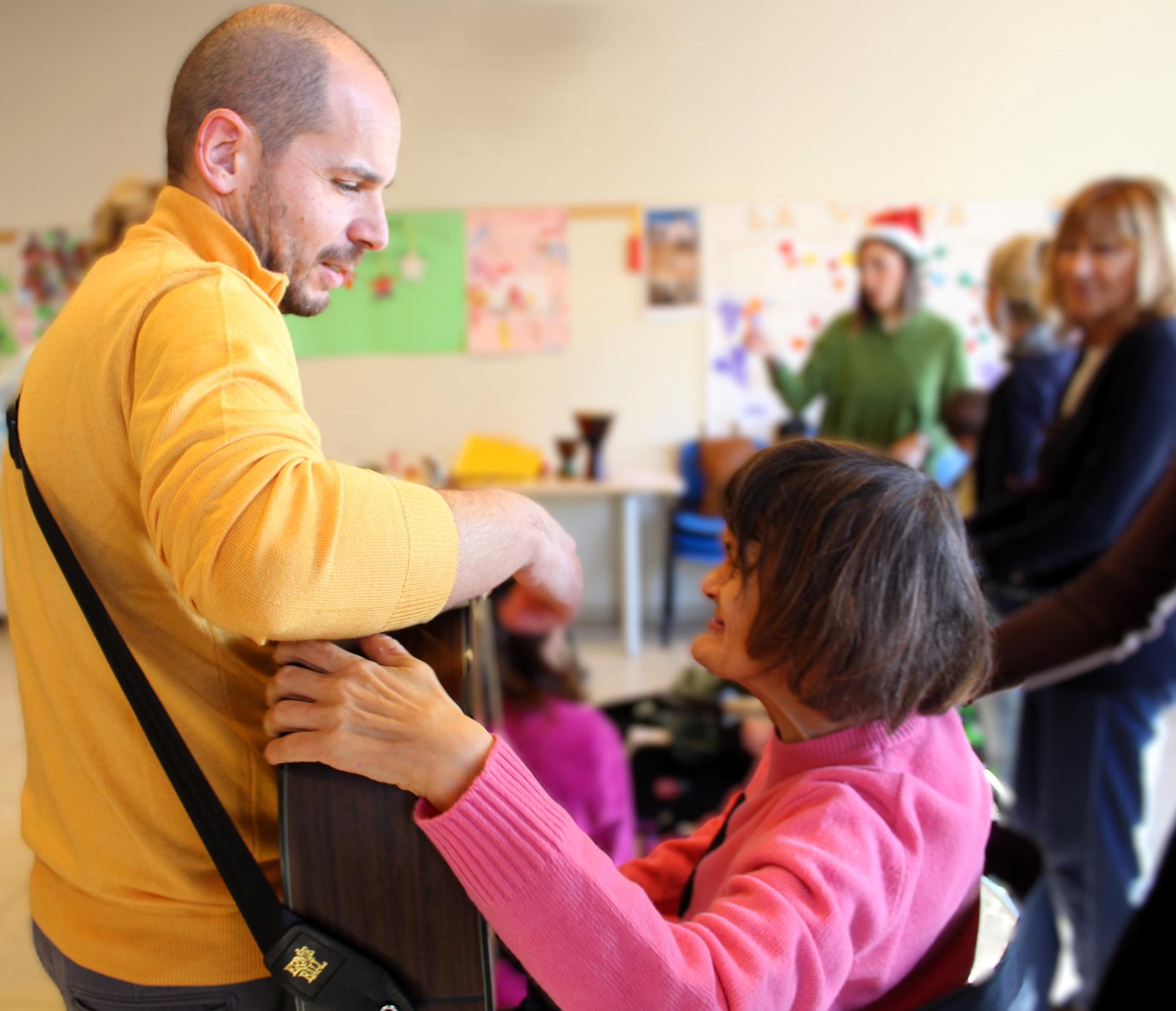 Un educatore avvicina la chitarra a un'utente per fargliela toccare