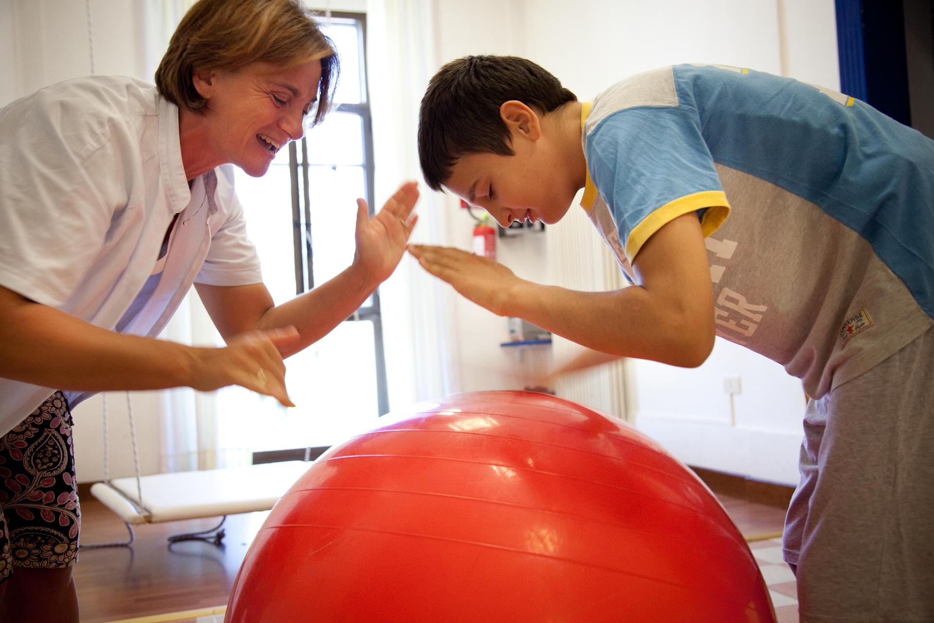 Utente seguito dalla Lega del Filo d'Oro, insieme all'educatrice, giocano con una grande palla rossa