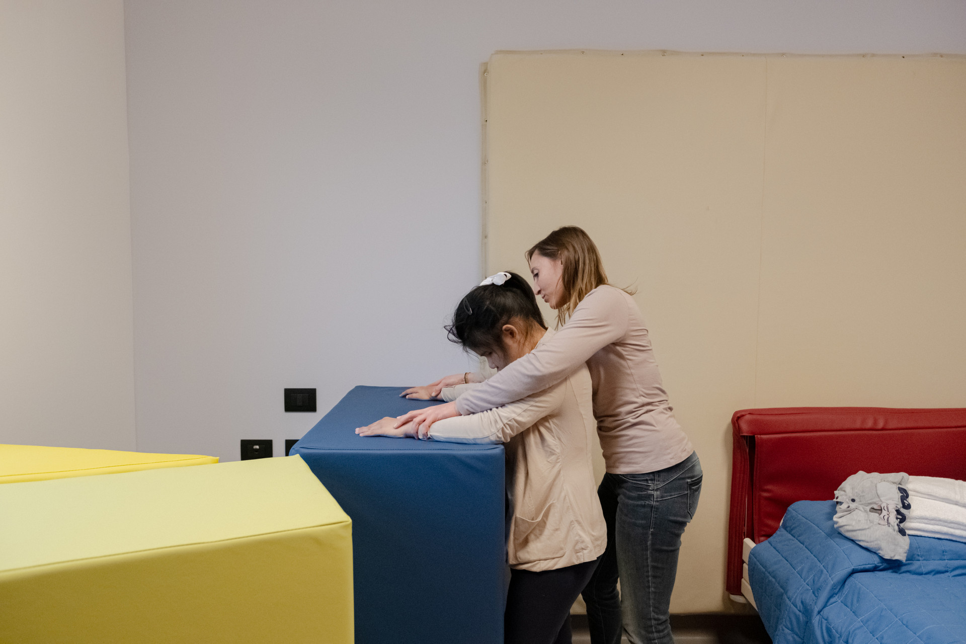 bambina utente ed educatrice toccano i materassi colorati nella stanza